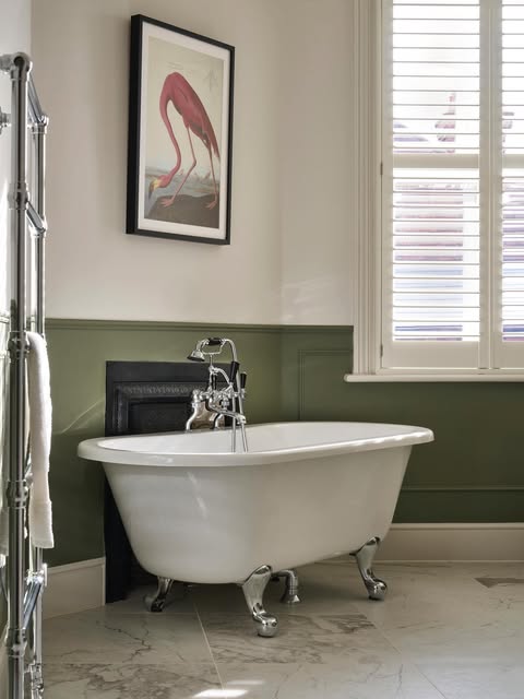 Bathroom with olive-green panelling, a roll-top bath on chrome feet and a framed flamingo print
