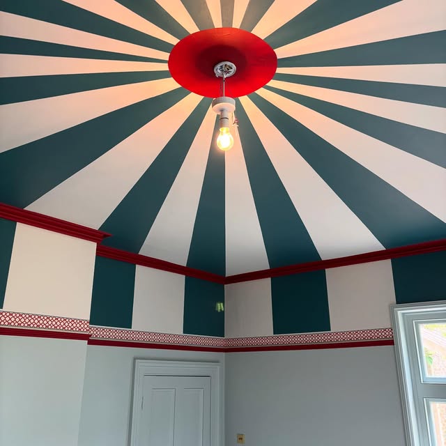 Striped ceiling hand-painted in teal and white radiating from a red ceiling rose